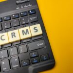 Black keyboard and toys word with the word CRMS on yellow background.