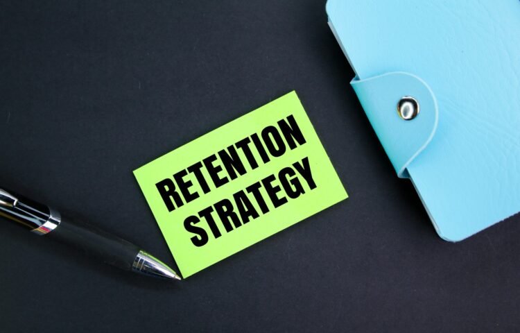 colored pen, book and paper with the word retention strategy.