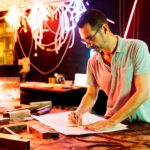Focused man preparing design on paper with pencil