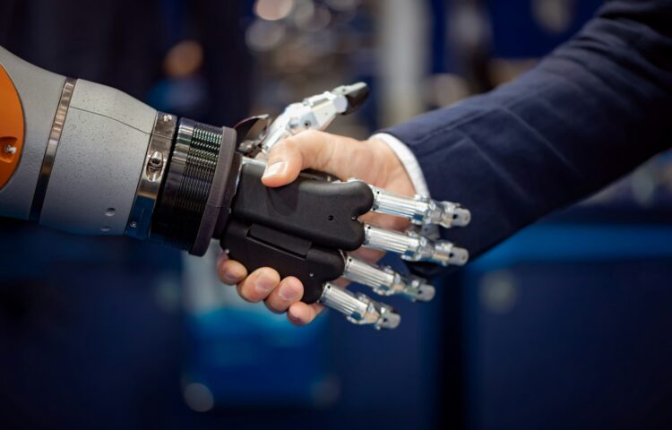 Hand of a businessman shaking hands with a Android robot.