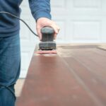 Man using an electric sander to refinish doors