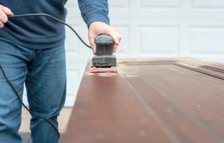 Man using an electric sander to refinish doors