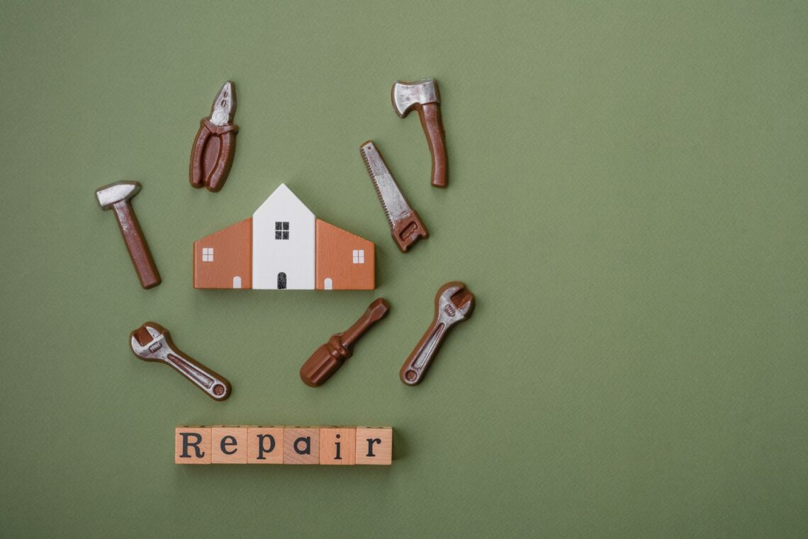 Repair or home improvement tools and a house model on a plain background