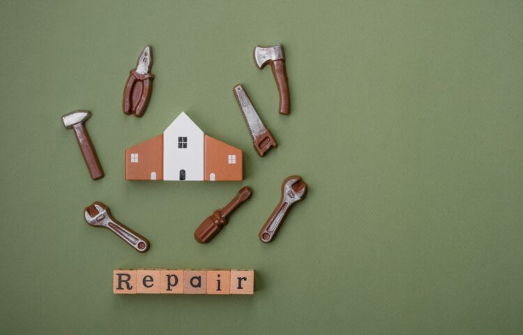 Repair or home improvement tools and a house model on a plain background