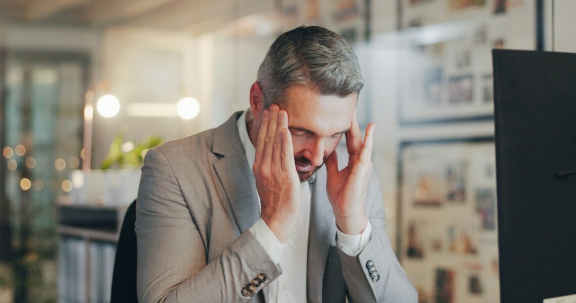 Stress, headache and mature man in office with computer, night work and frustrated with time manage