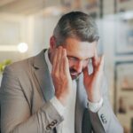 Stress, headache and mature man in office with computer, night work and frustrated with time manage