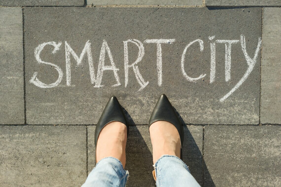 View from above, female feet with text smart city written on grey sidewalk.