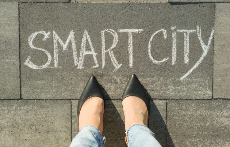 View from above, female feet with text smart city written on grey sidewalk.