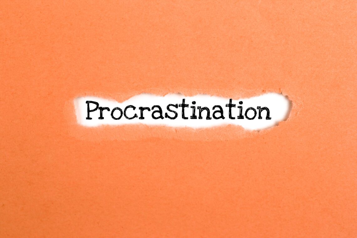a torn paper written with inscription procrastination on a orange background