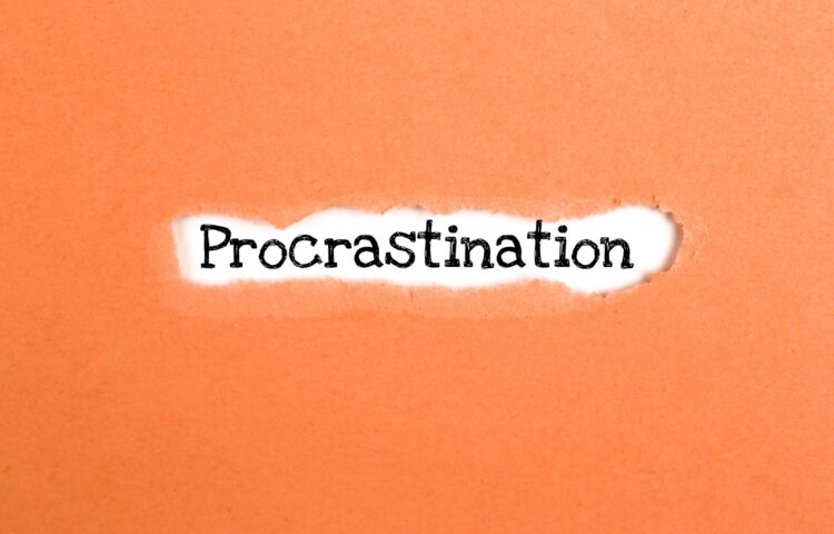 a torn paper written with inscription procrastination on a orange background