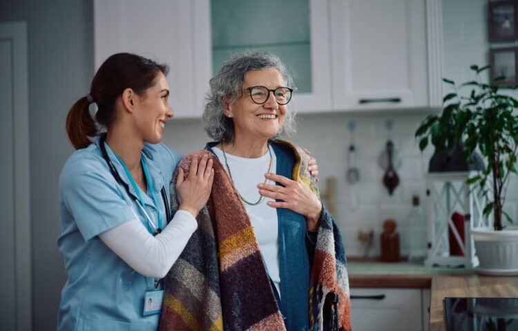 Caring nurse embracing senior woman during a home visit.