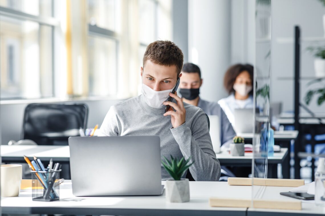 Social distance and online work with client remotely. Busy man in protective mask talking on smart