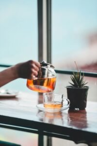 Pouring tea into a glass cup by a window