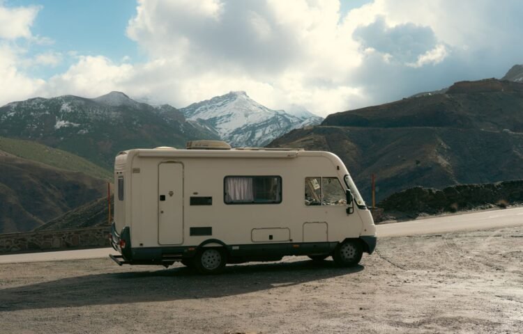 Camper van parked on a roadside with a snowy mountain backdrop