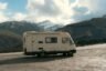 Camper van parked on a roadside with a snowy mountain backdrop